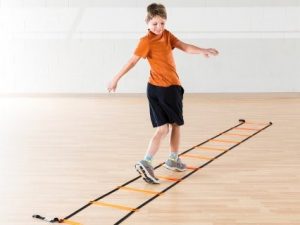 young boy stepping and twisting while using agility ladder